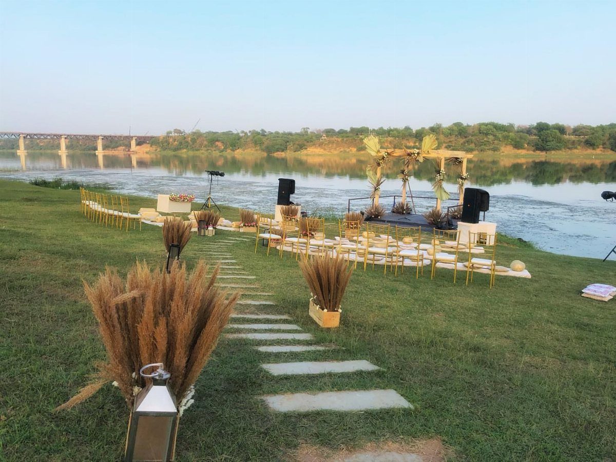 Wooden arbour decorated with pampas grass for a wedding ceremony by a river.