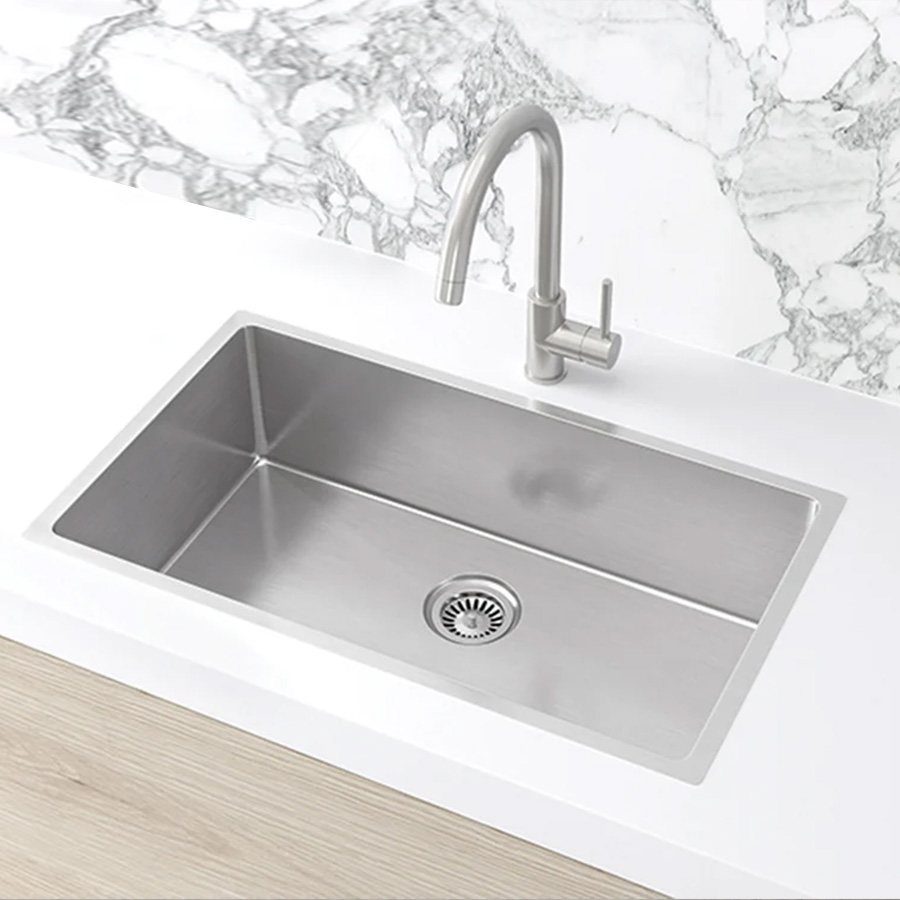 Stainless steel single basin kitchen sink with faucet and white marble backsplash.