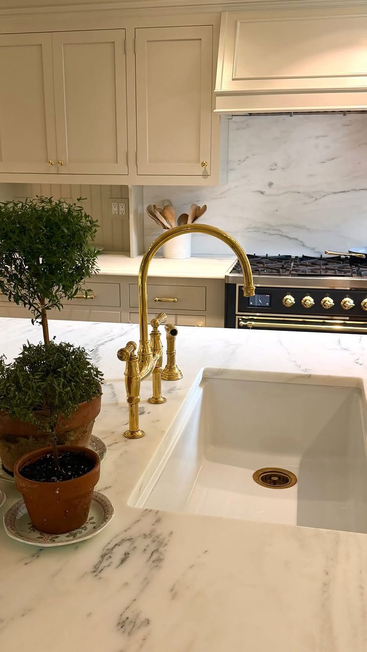 White undermount kitchen sink with gold faucet installed in a white marble countertop