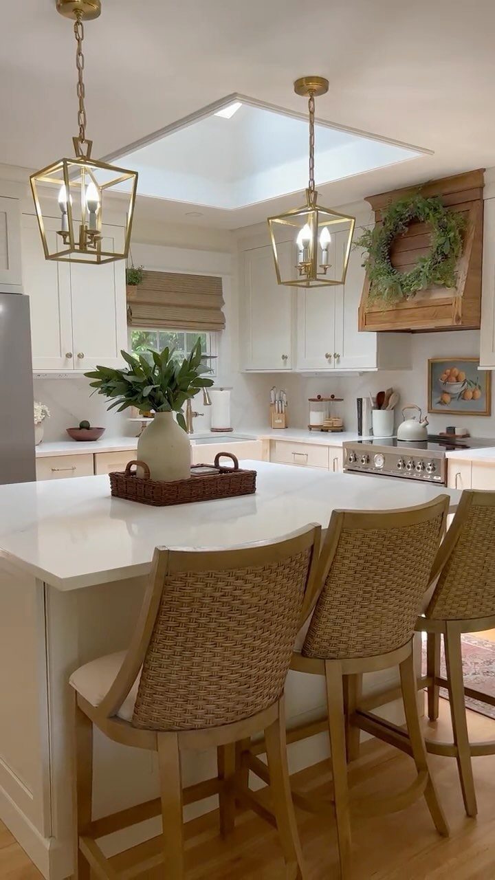 Two gold open-frame lantern pendant lights hanging over a white kitchen island.