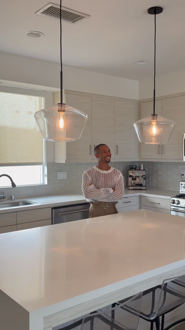 Man standing in a modern kitchen with two clear glass pendant lights over island
