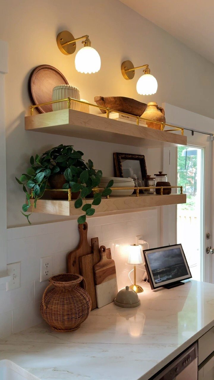 Gold wall sconces with white globe shades mounted above wooden kitchen open shelving