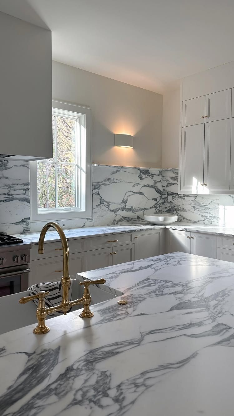 Wall sconce lighting next to a kitchen window with white marble countertops.