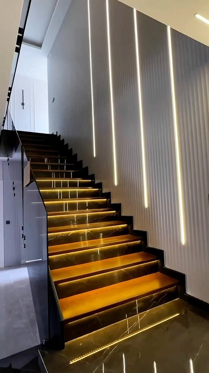 Modern stairwell with glowing under-step lights and vertical light strips on a white wall