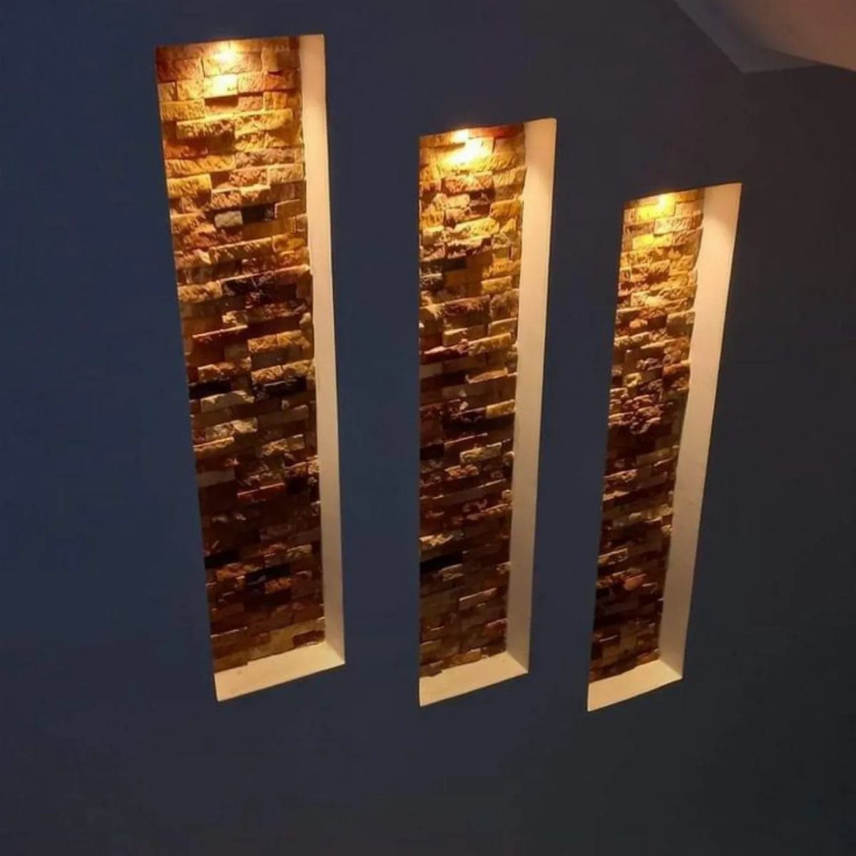 Three recessed wall niches with stacked stone interiors and warm overhead lighting.