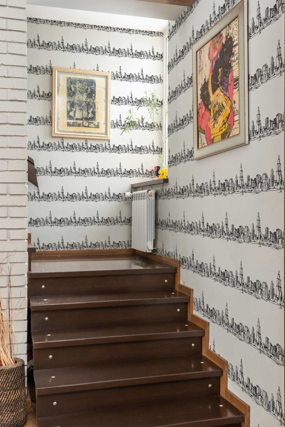 City skyline line art wallpaper on a white wall next to brown stairs.