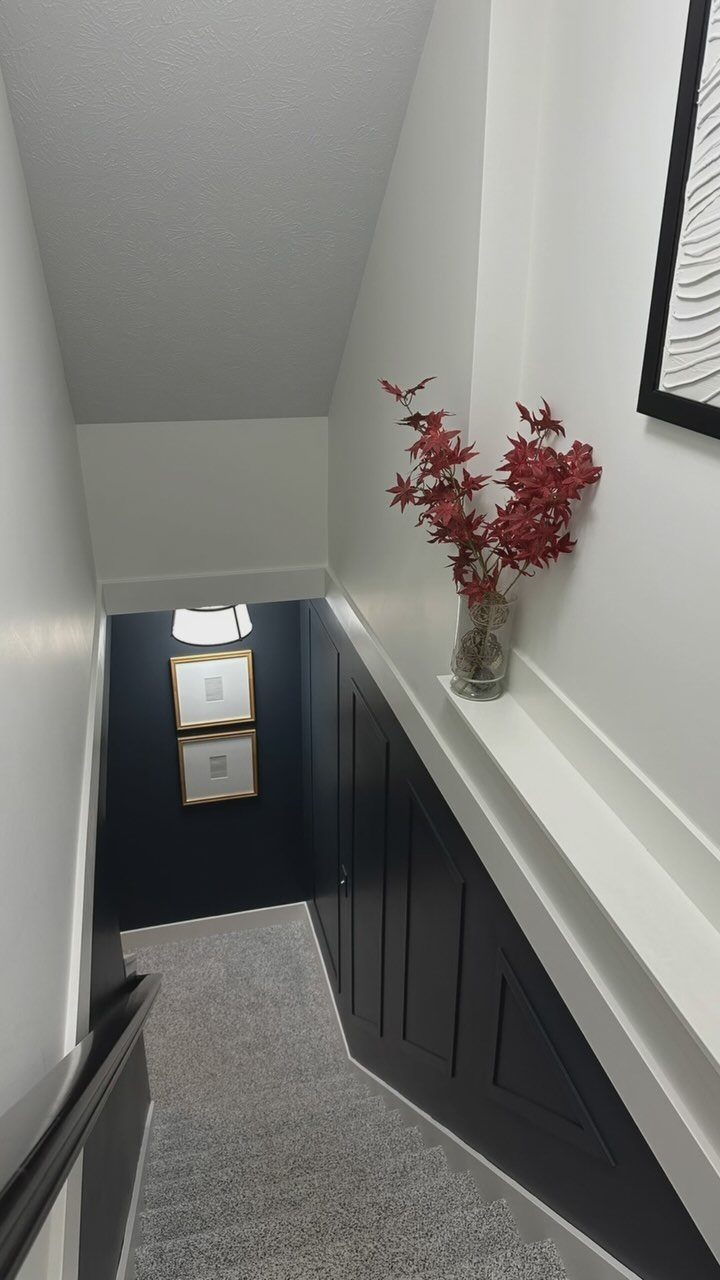 Dark navy blue accent wall in a stairwell with gold framed art.