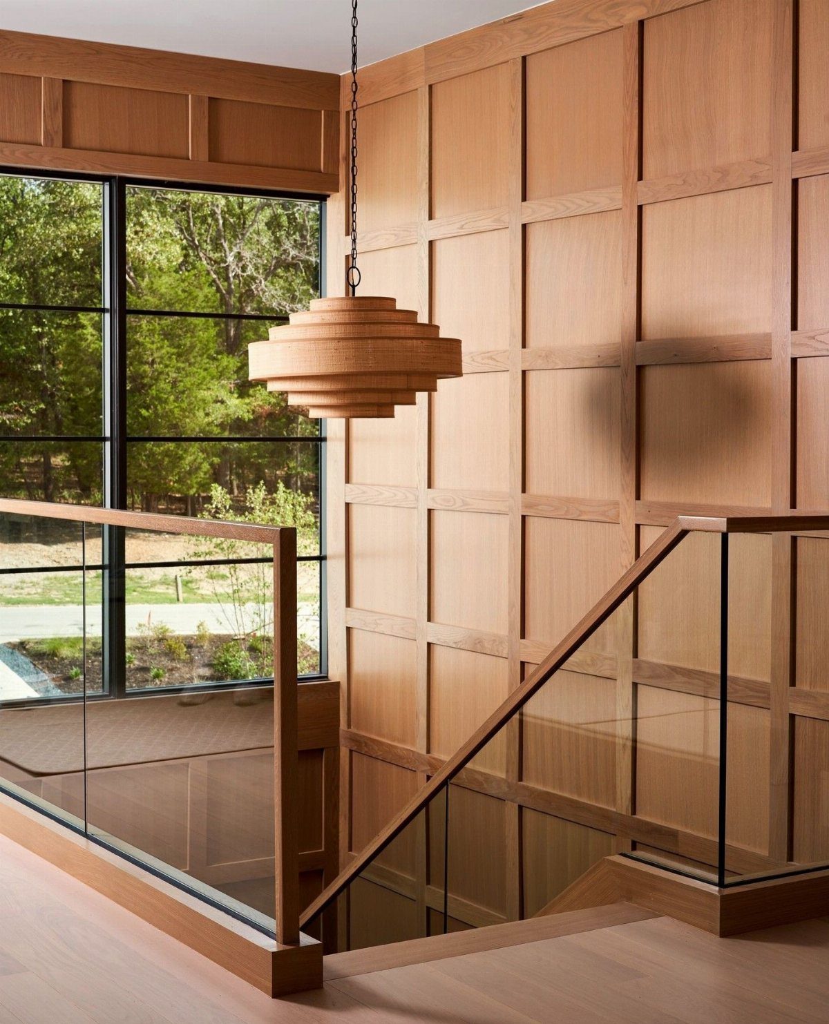 Natural wood grid paneling on a stairwell wall with a tiered wooden pendant light.