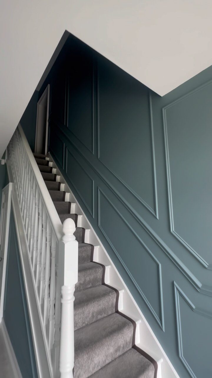 Navy blue paneled accent wall along a grey carpeted staircase with white railings.