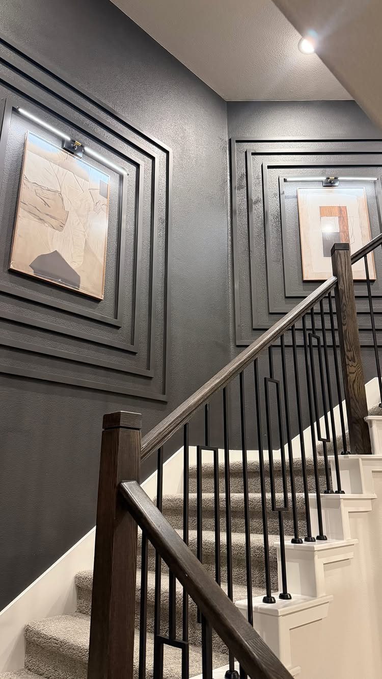 Dark grey stairwell walls with recessed rectangular molding and framed abstract art.