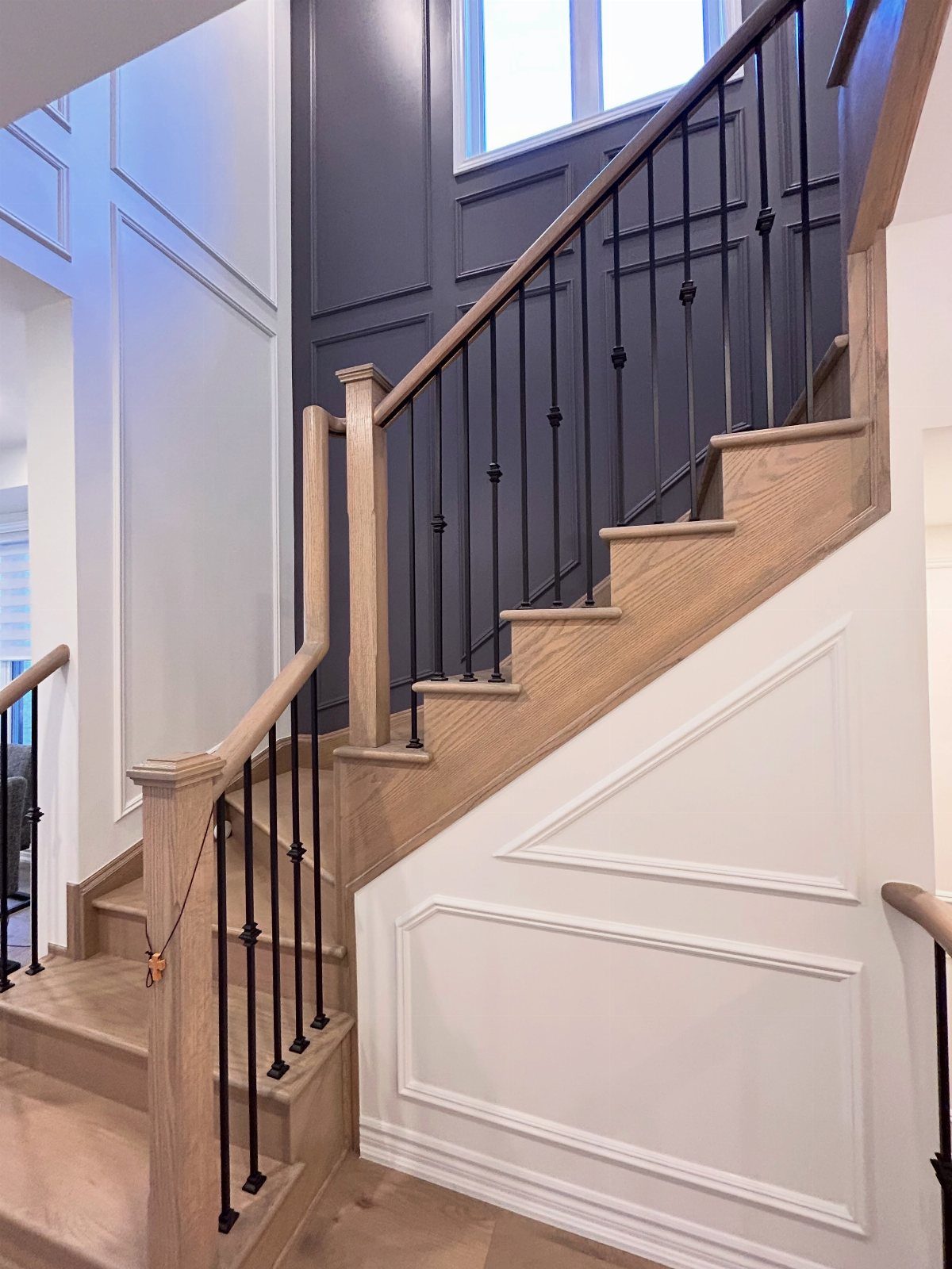 Stairwell with white decorative wainscoting on the lower wall and dark grey upper walls.