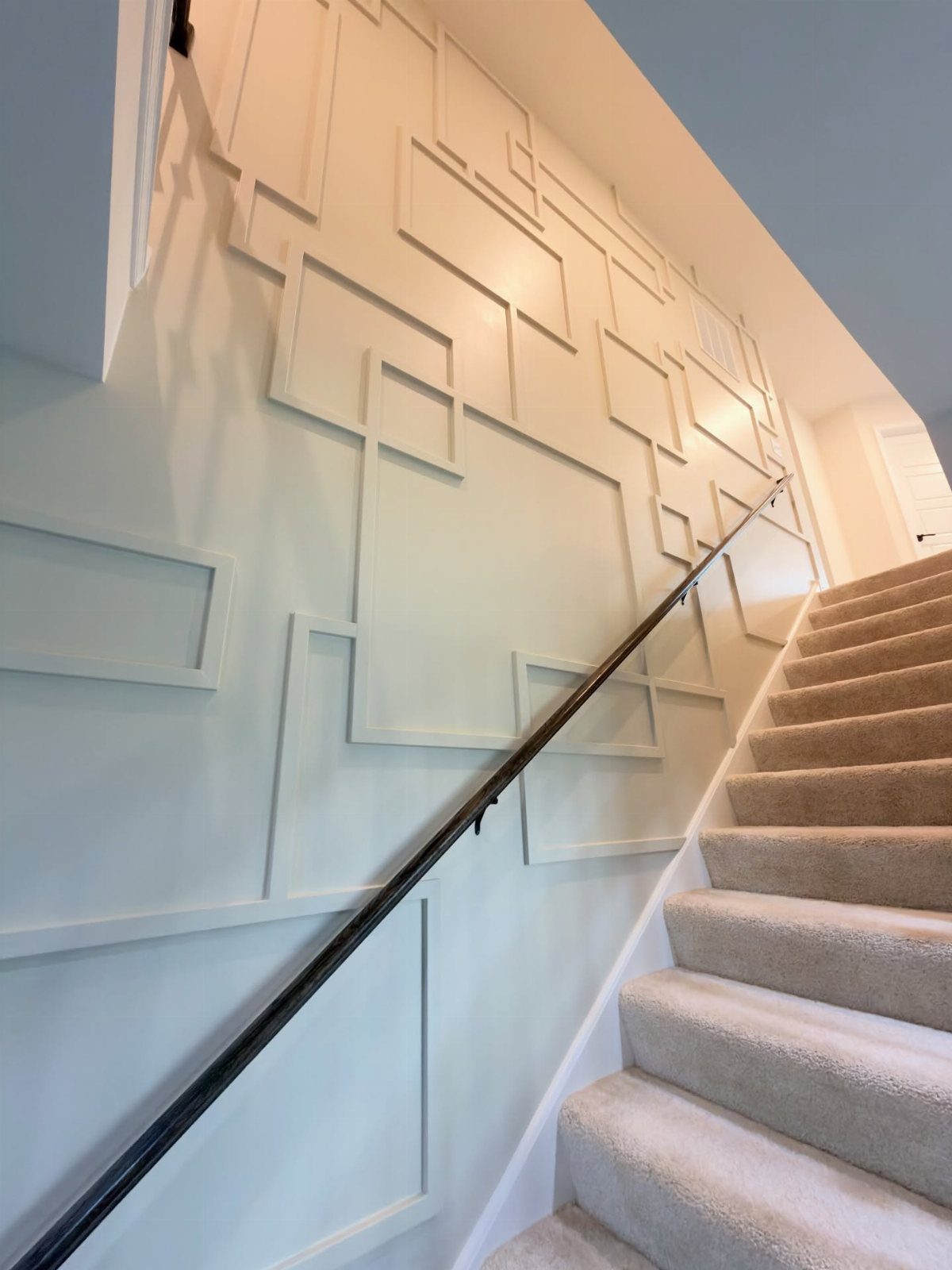 White geometric wood trim molding on a light gray stairwell accent wall.