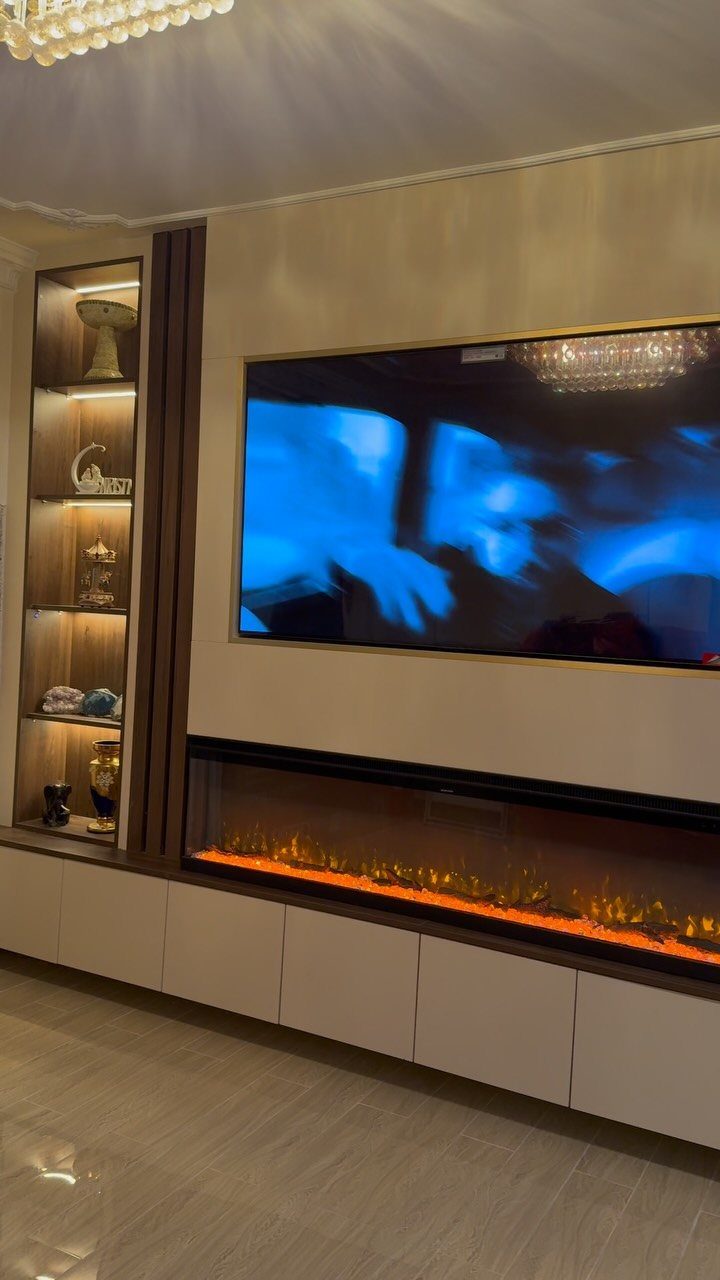 39 TV Design Ideas, from Built-In Shelving to Fireplace Walls 1 Wall-mounted television above a linear fireplace with built-in illuminated shelving on the side.