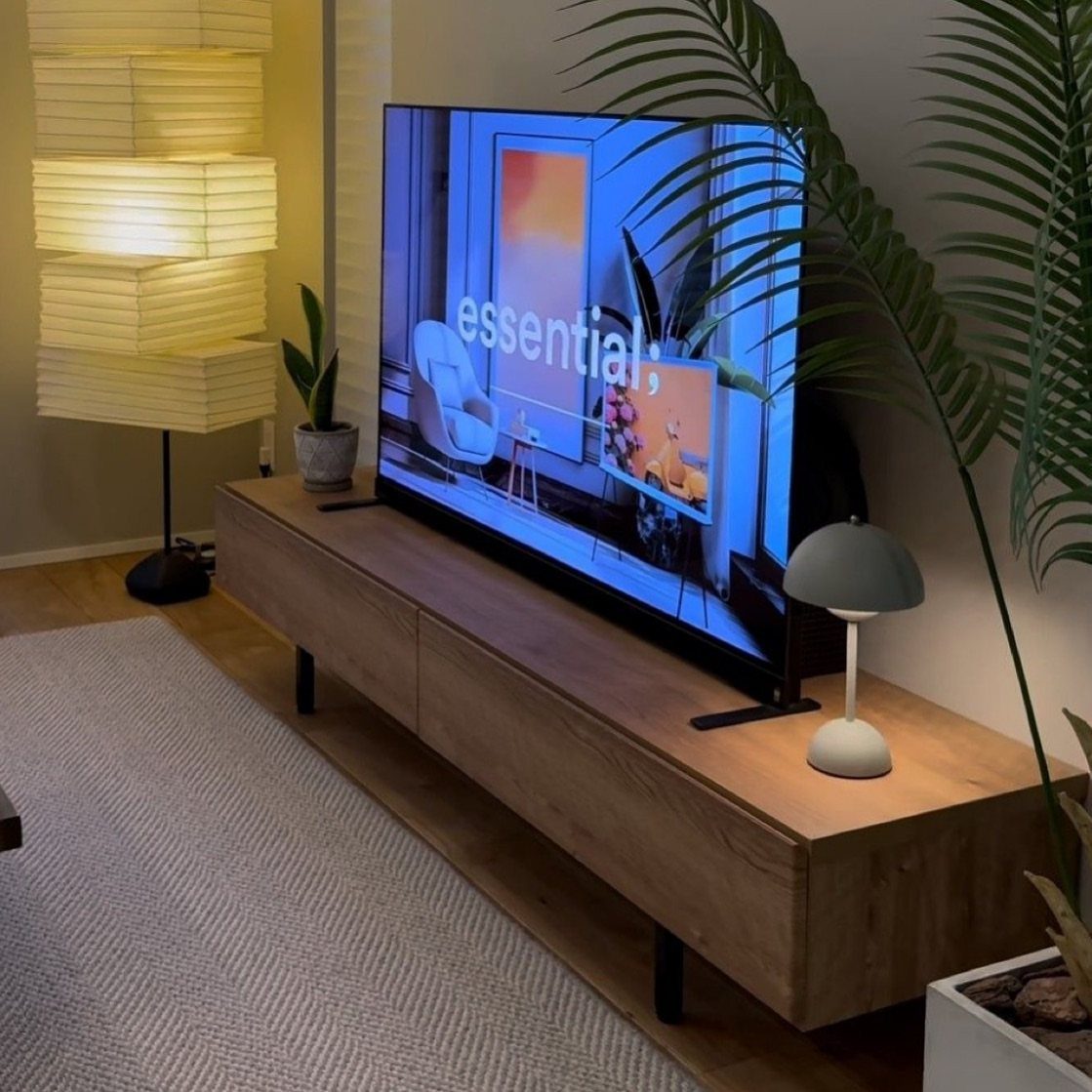 39 TV Design Ideas, from Built-In Shelving to Fireplace Walls 21 Flat-screen television on a low, wide wooden console in a modern living room.