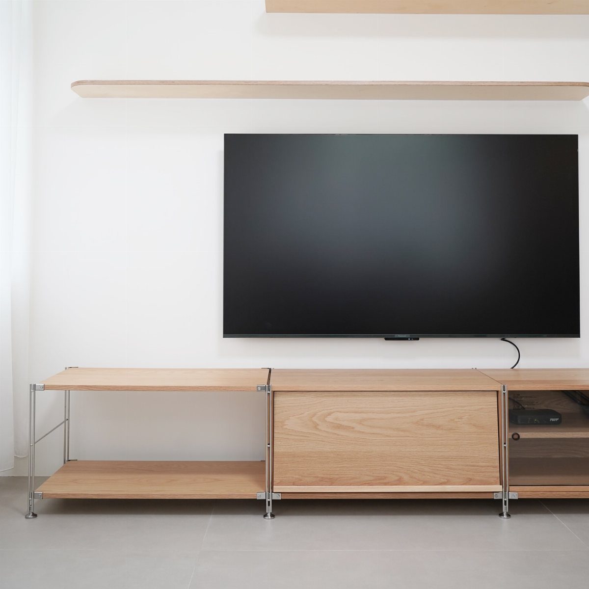 39 TV Design Ideas, from Built-In Shelving to Fireplace Walls 18 Wall-mounted TV above a light wood console with open shelves and a cabinet.