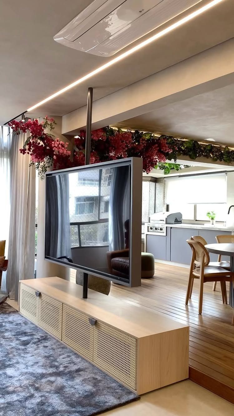 39 TV Design Ideas, from Built-In Shelving to Fireplace Walls 24 Television mounted on a rotating black pole above a light wood console unit.