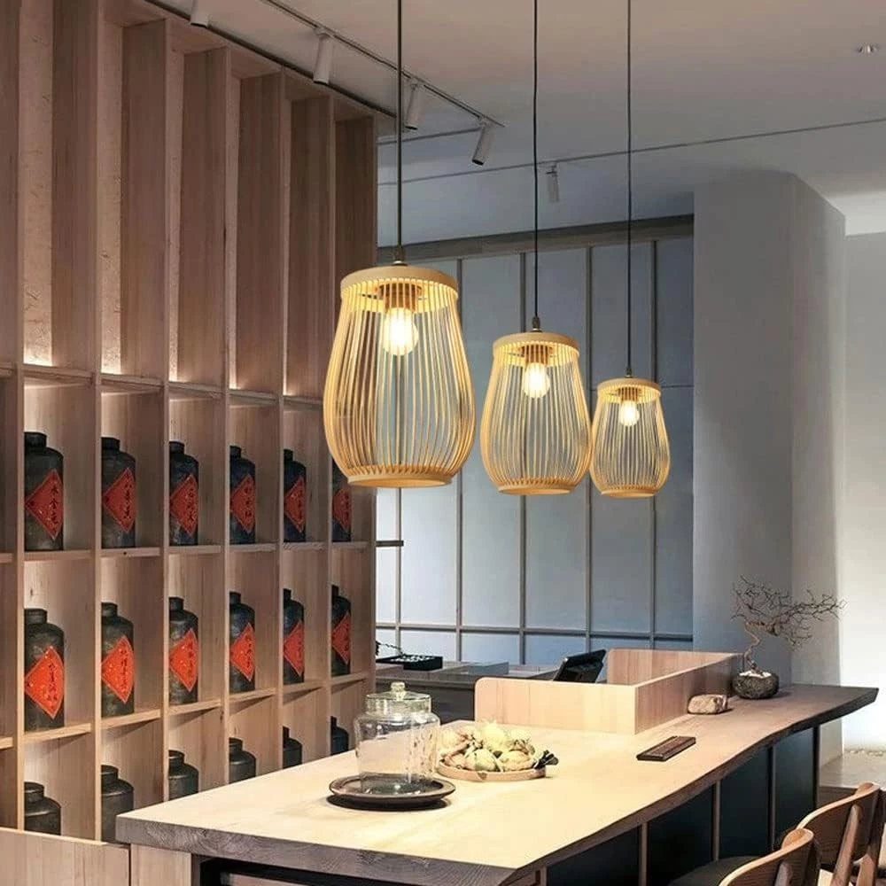 Three bamboo pendant lamps hanging over a light wood counter in a modern room.