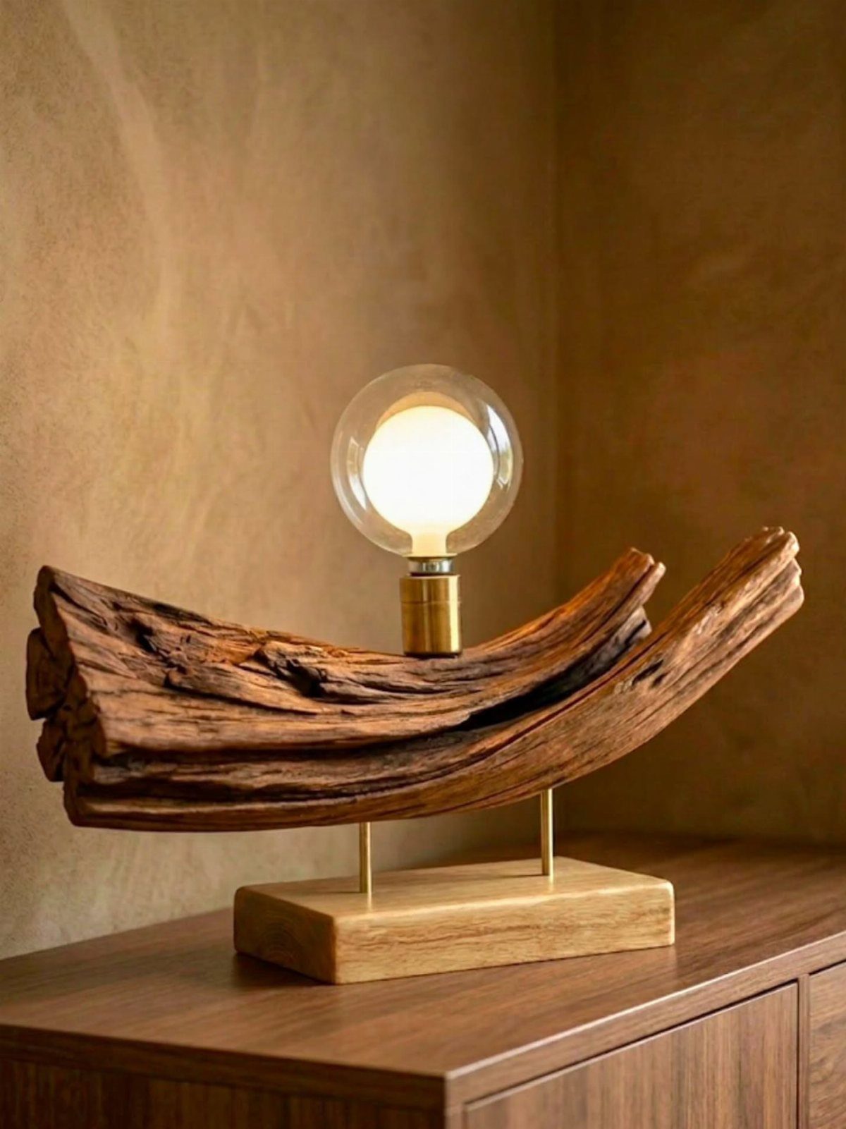 Driftwood table lamp with a glowing round bulb on a wooden base