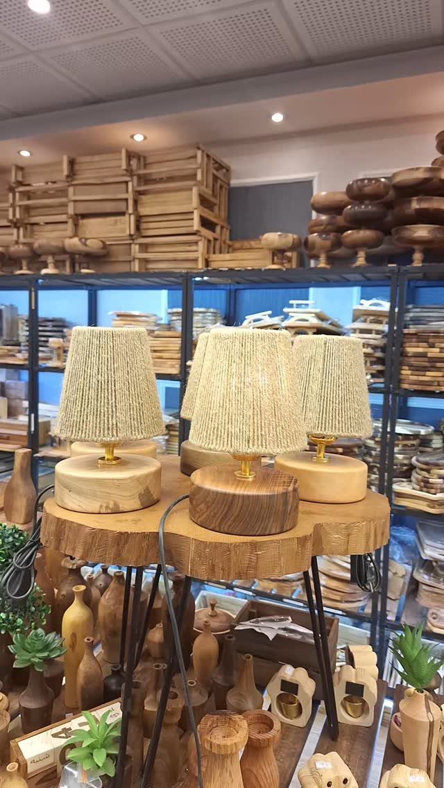 Three small table lamps with fabric shades and wooden bases on a wooden shelf.
