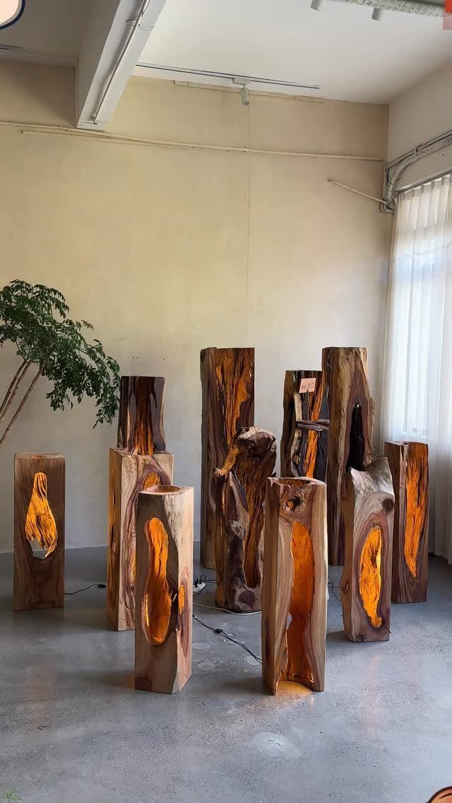 Wooden sculptures with glowing orange interiors arranged in a bright, minimalist room.