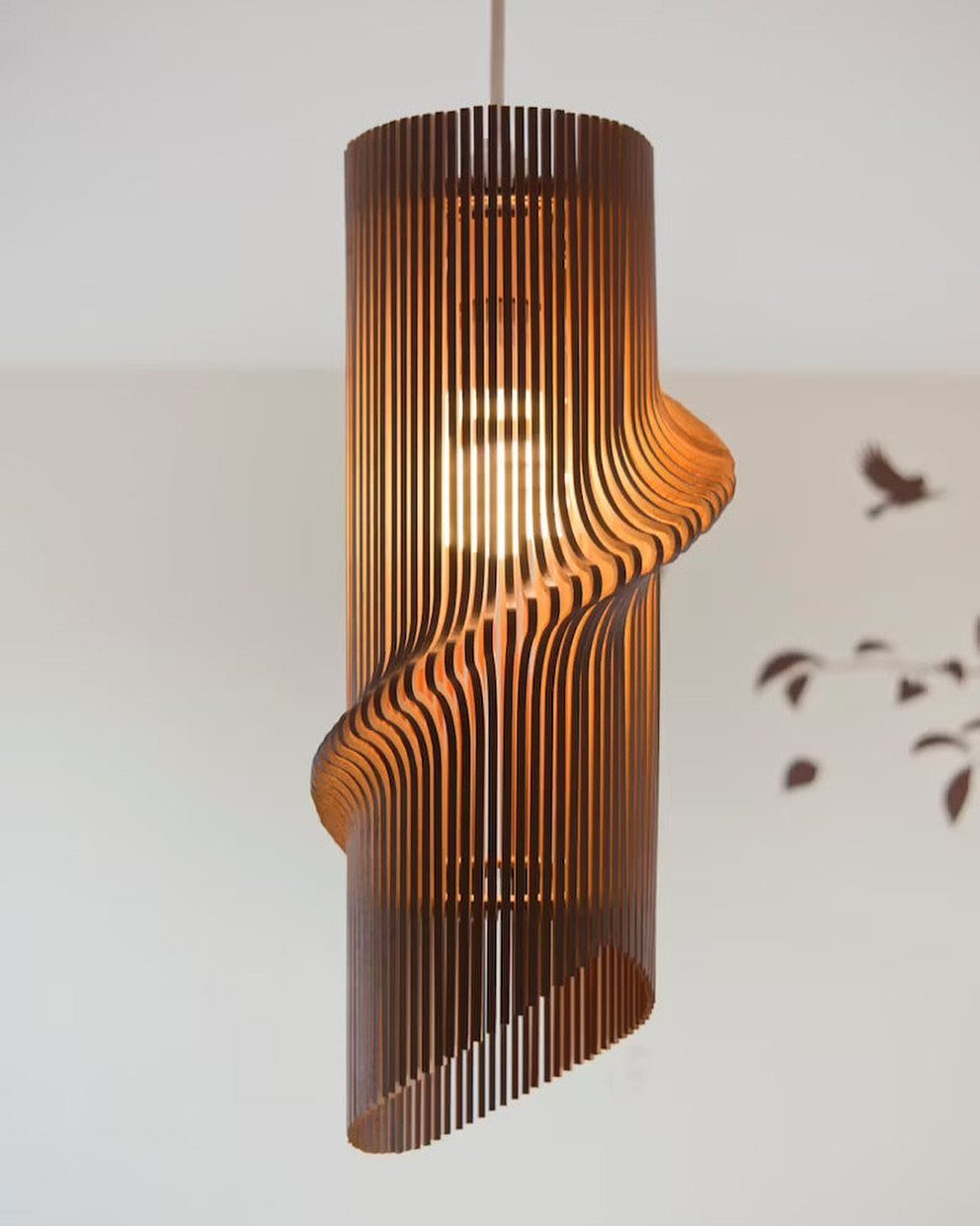 Cylindrical pendant lamp with twisting brown wooden slats and a glowing interior bulb.