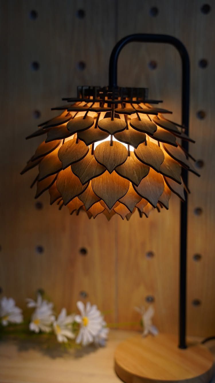Wooden lamp with layered petal shade and black metal arm on wooden base