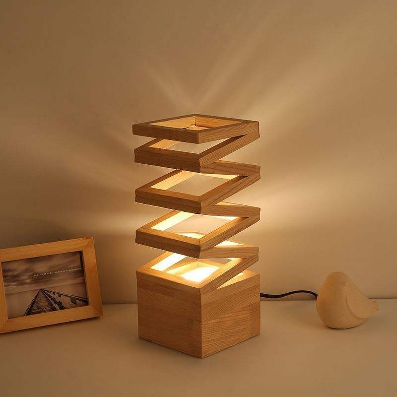 Spiral wooden table lamp with glowing square frames on a neutral surface