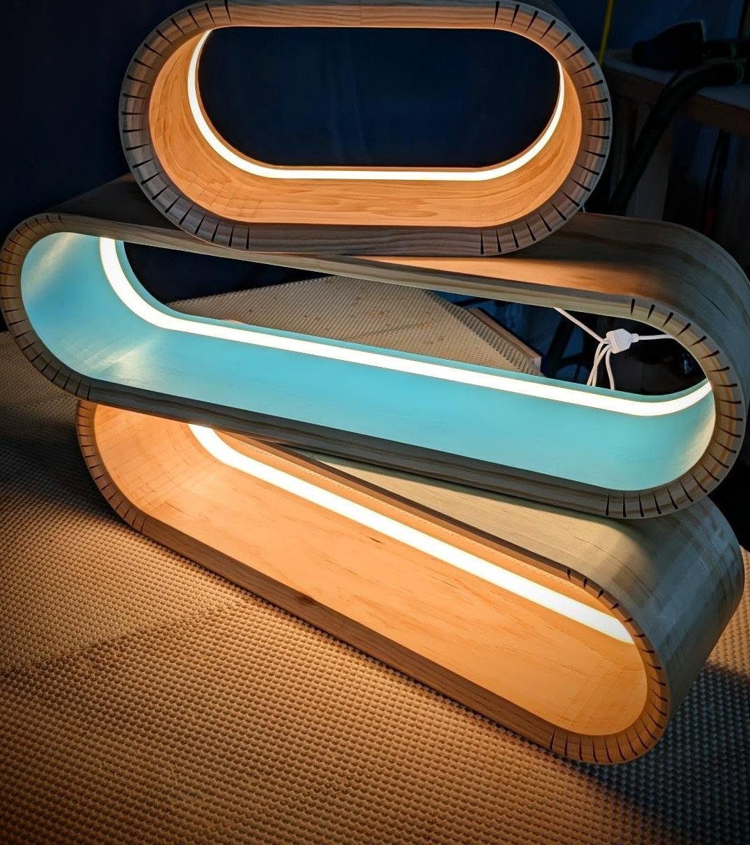 Curved plywood lamp with glowing blue and white LED light strips in a loop