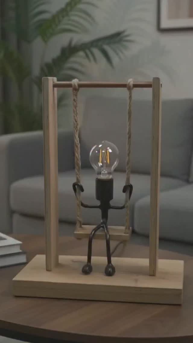Wooden lamp with a light bulb figure sitting on a rope swing.