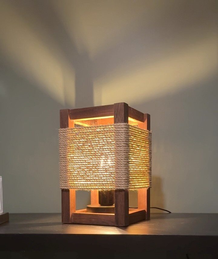 Wooden lamp with twine wrapping casting warm light against a neutral wall