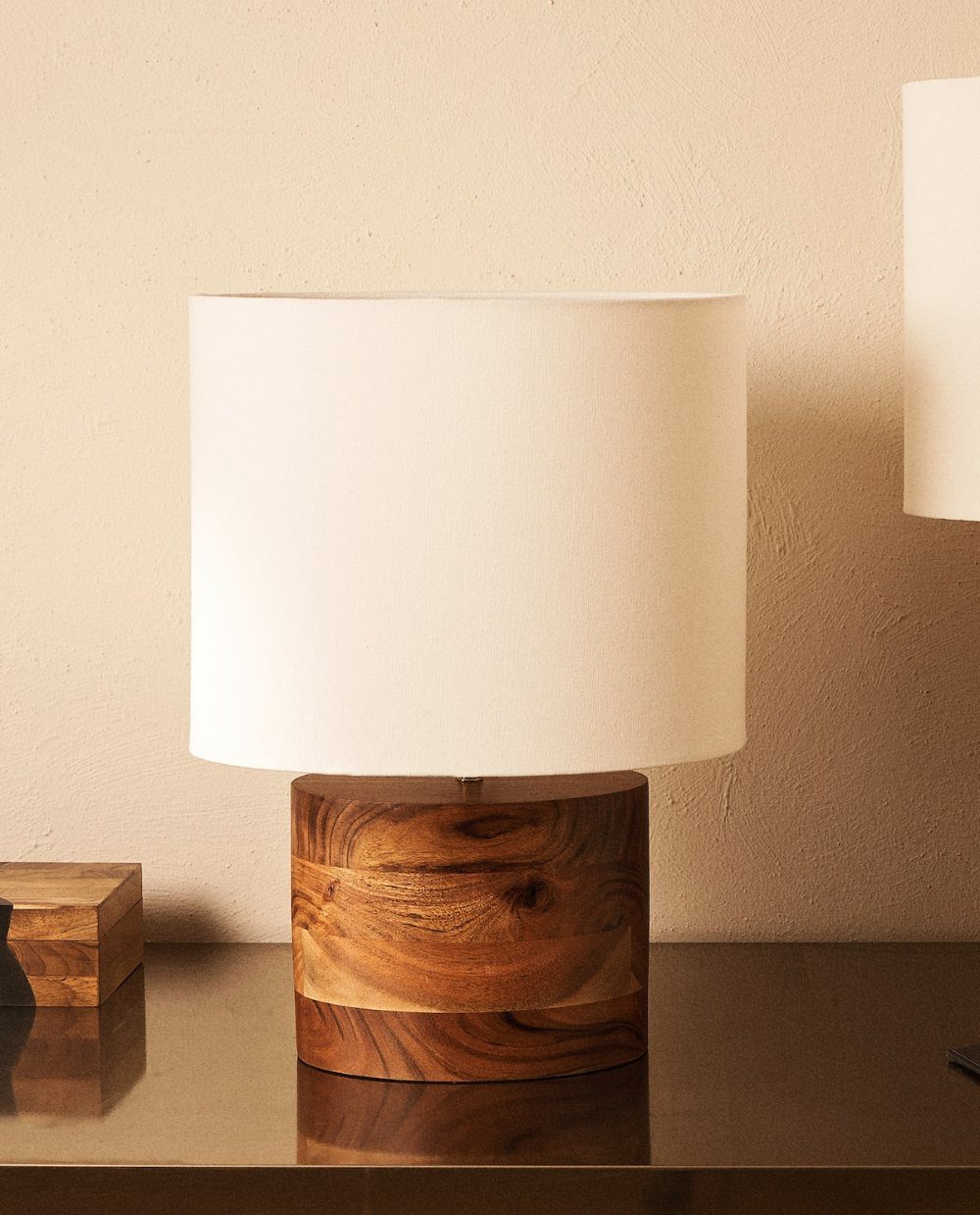 Table lamp with a chunky cylindrical wood block base and white fabric shade.