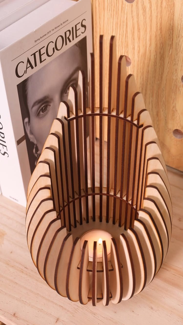Egg-shaped wooden slat lamp with a glowing candle inside on a wooden table