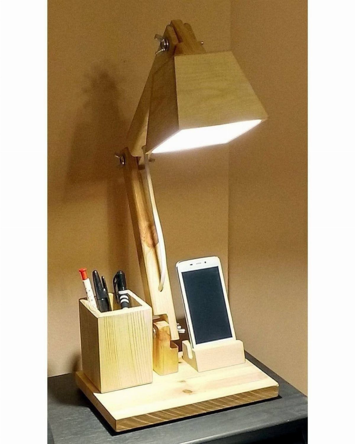 Wooden desk lamp with integrated pen holder and smartphone stand on a base.