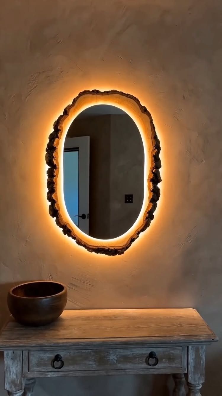 Oval mirror with a rustic wooden frame and warm orange backlight on a wall