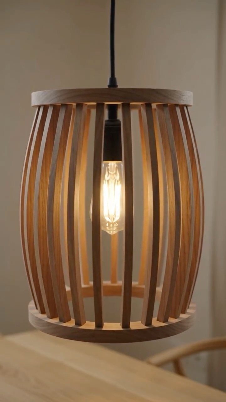 Wooden pendant lamp with a slatted cage shade and glowing Edison bulb.